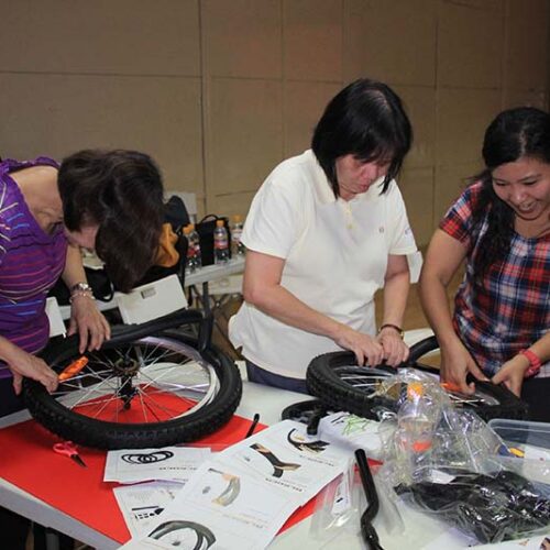 Corporate team collaborating on bike assembly during a CSR event.